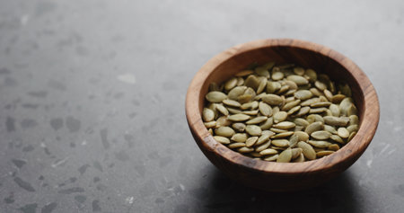 pumpkin seeds in olive bowl on terrazzo countertop with copy spaceの写真素材