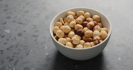 roasted hazelnuts in white bowl on terrazzo countertopの写真素材