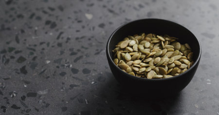 pumpkin seeds in black bowl on terrazzo countertop with copy spaceの写真素材