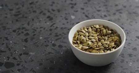 pumpkin seeds in white bowl on terrazzo countertop with copy spaceの写真素材