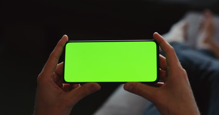 young man holding smartphone laying on a couchの写真素材