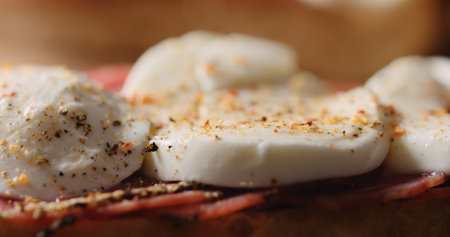 Extreme closeup freshly ground spices on salami mozzarella sandwich