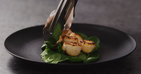 put roasted scallops on spinach in black plateの写真素材