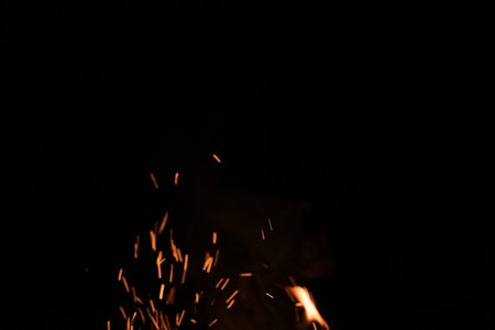 Sparks from campfire over dark background in the night