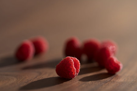 Fresh ripe raspberries on walnut wood table closeup