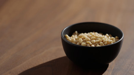 Pine nuts in a black bowl on wood table closeupの写真素材