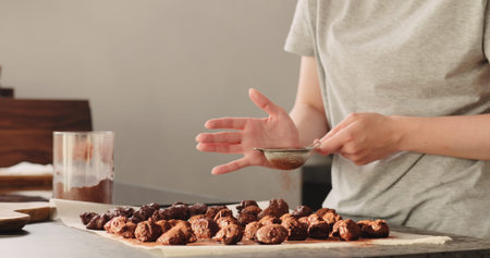 young woman sprinkle cocoa powder on chocolate truffles