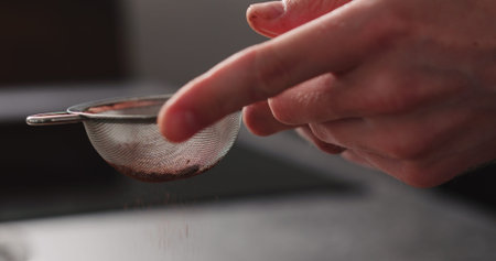 man hand sprinkle cocoa powder from sieve