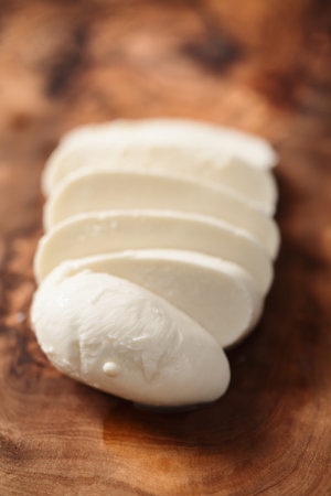 sliced mozzarella cheese on olive wood board