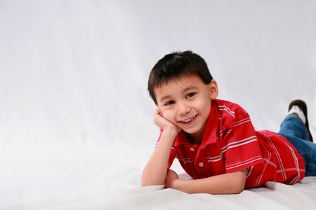 studio shot of cute asian boy laying on stomachの写真素材