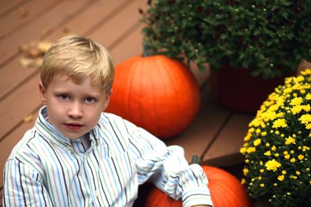cute blonde boy sitting by pumpkinの写真素材