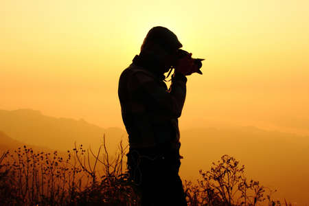 Silhouette of a young photographer during the sunset at PHU CHEEFA PARK , Chiangrai in Thailandの写真素材