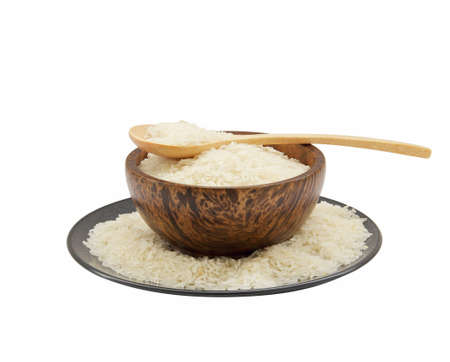 Thai jasmine raw rice in wooden spoon, wood bowl and ceramic plates on white backgroundの写真素材