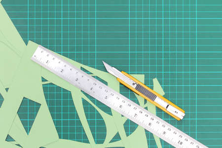 Cutter yellow handle ,metal ruler and paper being cut , Placed on the green cutting mat