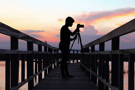 Silhouette of a photographer on the wooden bridge at Khao Sam Roi Yot National Park in Thailand during the sunsetの写真素材