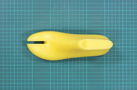 Yellow plastic last shoe rough surface from use on green grid pattern background of cutting mat(with clipping path)の写真素材
