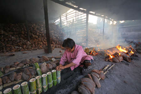 Old women are doing glutinous rice roasted in bamboo joint "Khaolam" at Chonburi province in Thailand on on may 04, 2013 : "Khaolam" as the main meals and snacks of the Thai peopleのeditorial素材
