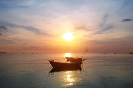 Silhouette natural background of small fishing boats moored beached on the beach during time the sunset and the beautiful natural of the colorful sky at BangPhra beach , Chonburi province in Thailandの写真素材