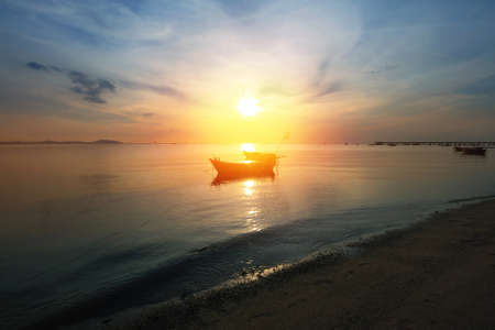 Silhouette natural background of small fishing boats moored beached on the beach during time the sunset and the beautiful natural of the colorful sky at BangPhra beach , Chonburi province in Thailandの写真素材