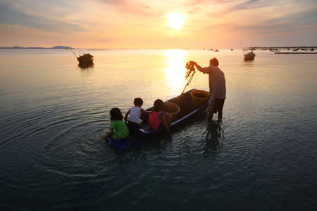 Silhouette scenery of the livelihoods of fishermen during time the sunset and the beautiful natural of the colorful sky at Bang Phra beach , Chonburi province in Thailand.の写真素材
