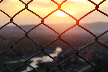 Mesh fence close-up on a blurred background of Beautiful scenery during time the sunset. The nature and the freedom conceptの写真素材