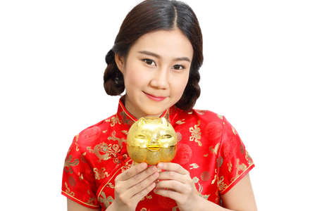 Asian lady in red cheongsam dress(qipao) holding gold piggy bank Isolated on white background. Saving Money concept.の写真素材