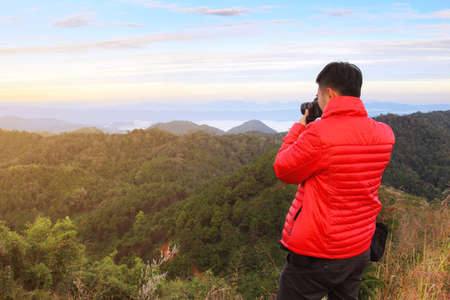 Photographer men standing outdoor photography amidst the beautiful scenery of mountain view from top of Doi Pha Phung at Nan province in Thailand. travel and natural Concepの写真素材