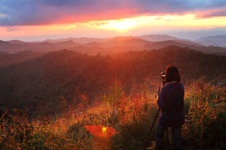 Photographer woman standing outdoor photography amidst the beautiful scenery of mountain and meadow...