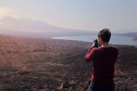 Photographer men standing outdoor photography amidst the beautiful nature of Mt. Fuji at Yamanashi in Japan. Travel and Attractions Concept.の写真素材