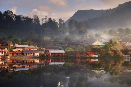 Beautiful scenery during sunrise with the mist and water reflection of the Chinese village at the...