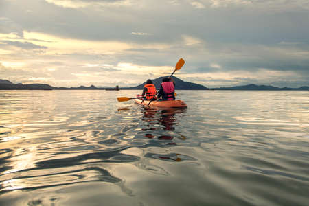Tourist paddling the kayak on the sea among the beautiful scenery during sunset at koh pitak , chumphon province in Thailand. This is very popular for photographers and tourists.の写真素材
