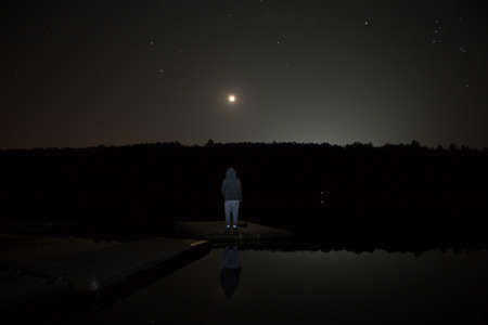 Man contemplating by the lake under full moon and bright stars. Photographed in Willington, CT, USA...