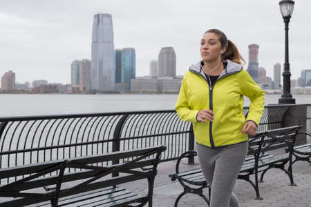 Young woman jogging by Hudson River while listening to music. Photographed on October, 2015.の写真素材
