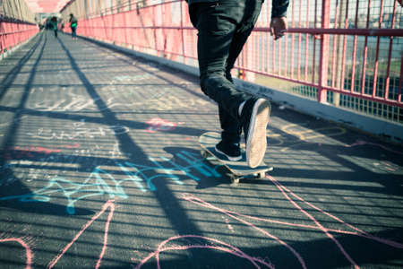 Young skateboarder speed through the pedestrian walkway on Williamsburg Bridge, NYC. Photographed in Feb 2016.の写真素材