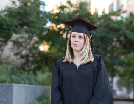 Portrait of female college student on campus in graduation day, looking worried and confused