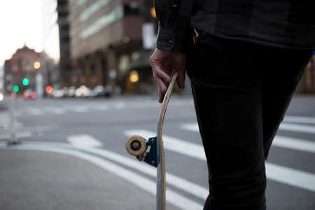Back figure of a man with a skateboard at cross walk. Photographed in NYC in March 2016.の写真素材