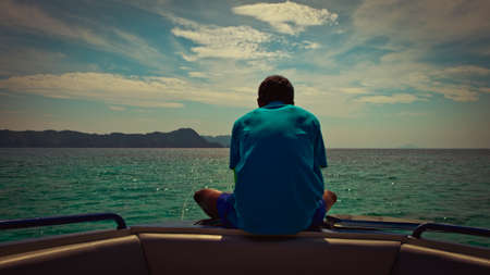 A man sitting lonely on boat  looking at horizonの写真素材
