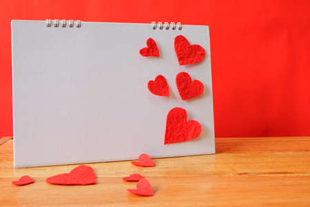 valentine day with calendar concept, red heart shape on white blank calendar,wooden table and red backgroundの写真素材