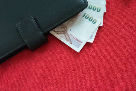 black wallet and Thai banknote on red background, thai money on red background
