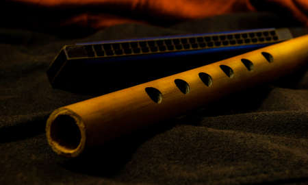 Musical instrument bamboo flute and harmonica placed on a dark backgroundの写真素材
