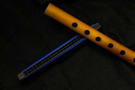 Musical instrument bamboo flute and harmonica placed on a dark backgroundの写真素材