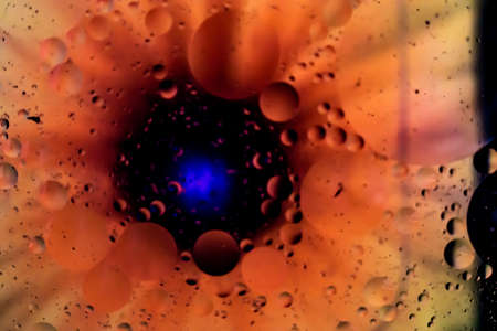 Closeup shot of oil on water with a orange and black backgroundの写真素材