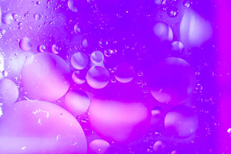 Closeup shot of oil on water with a violet backgroundの写真素材