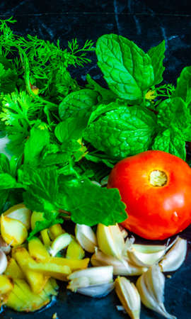 Fresh vegetables ready to be cooked kept on a black table with water splashesの写真素材