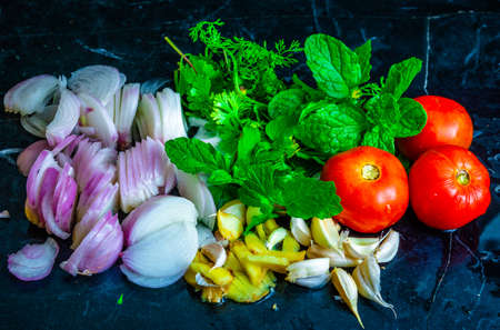 Fresh vegetables ready to be cooked kept on a black table with water splashesの写真素材