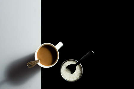 A cup of tea and and sugar with work space around on a black and white backgroundの写真素材