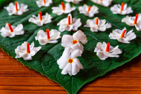 Beautiful parijatham flowers on a green leaf with wooden background