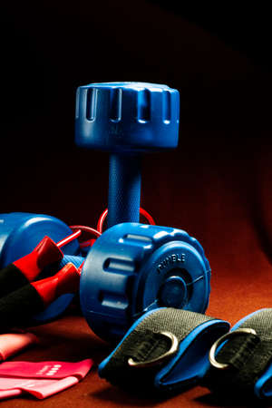 A pair of fitness equipment blue dumbbells resistance bands and skipping rope kept on a tableの写真素材