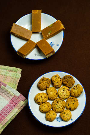 Barfi and cookies in a white plate on a brown backgroundの写真素材