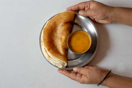 Homemade tasty and healthy dosa and sambar with human hands